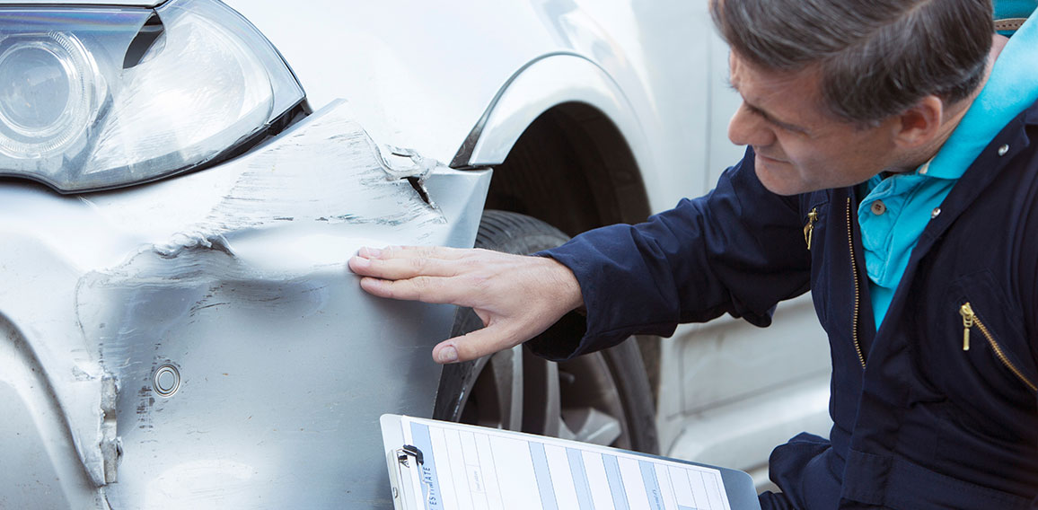 Auto Workshop Mechanic Inspecting Damage To Car And Filling In R