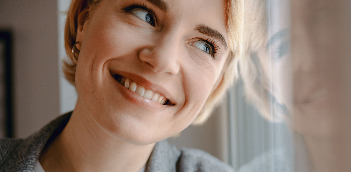 Smiling attractive woman is standing near window