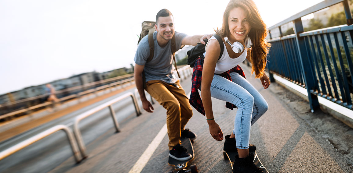 Young attractive couple riding skateboards and having fun