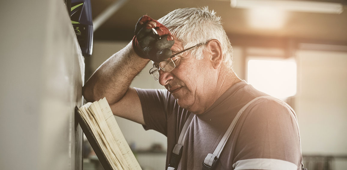 Senior man in workshop. Worried  man reading his planner.