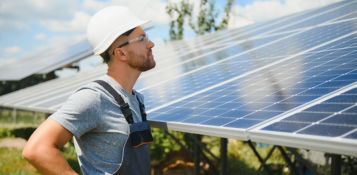 Male engineer in protective helmet installing solar photovoltaic panel system. Alternative energy ecological concept.