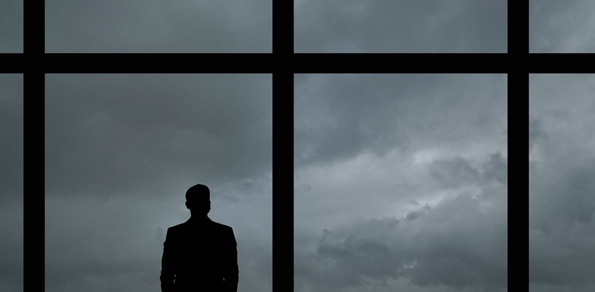 The man with suitcase standing near the big windows in the busin