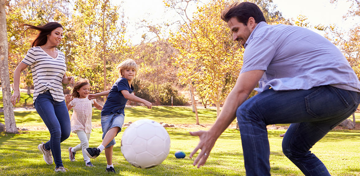 Family Playing Soccer In Park Together