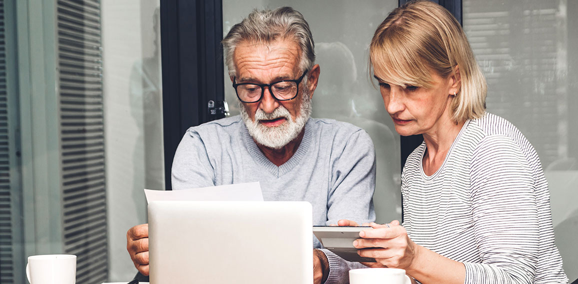 Senior couple reading documents and calculating bills to pay in