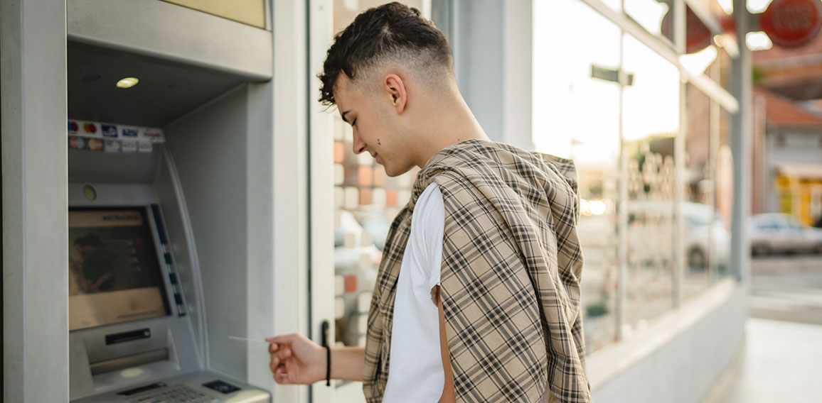 man teenage student using credit card and withdraw cash at the A