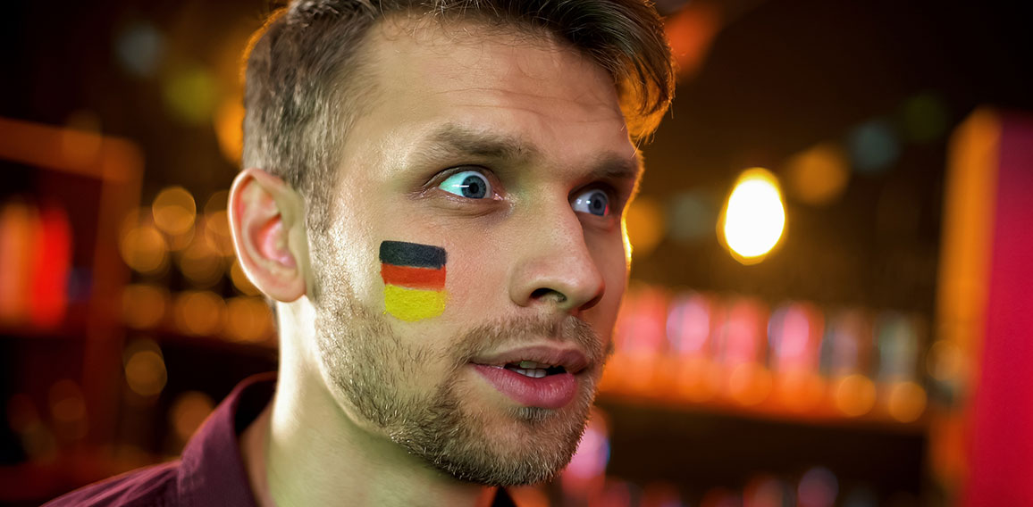 Bearded man with painted german flag surprised with results of championship