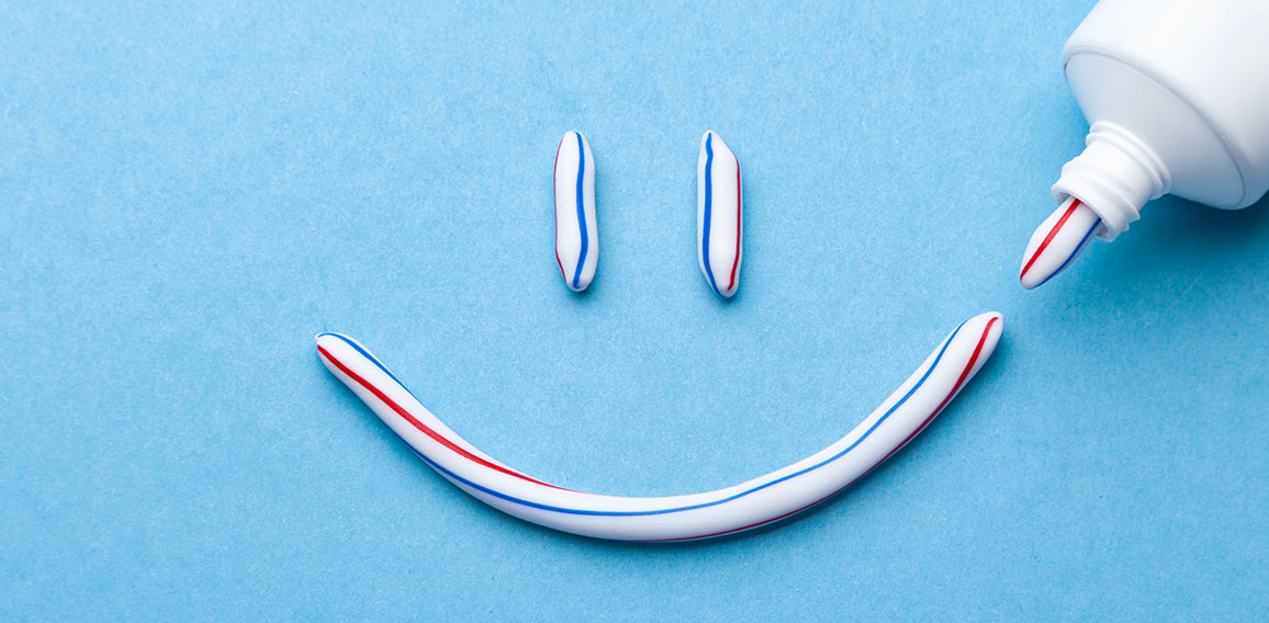 Tooth-paste in the form of a face with a smile. Tube of toothpas