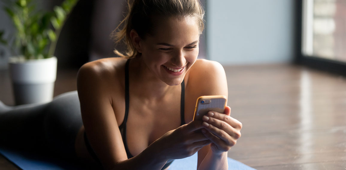 Young sporty woman holding smartphone, using app