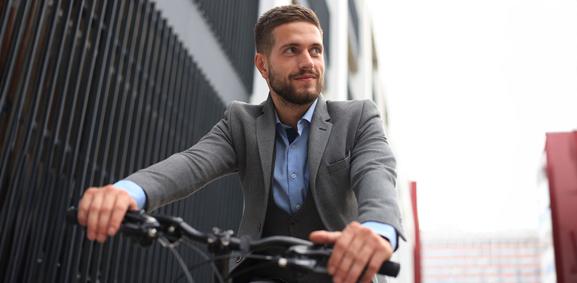 Handsome young businessman riding bicycle outdoors in the city.