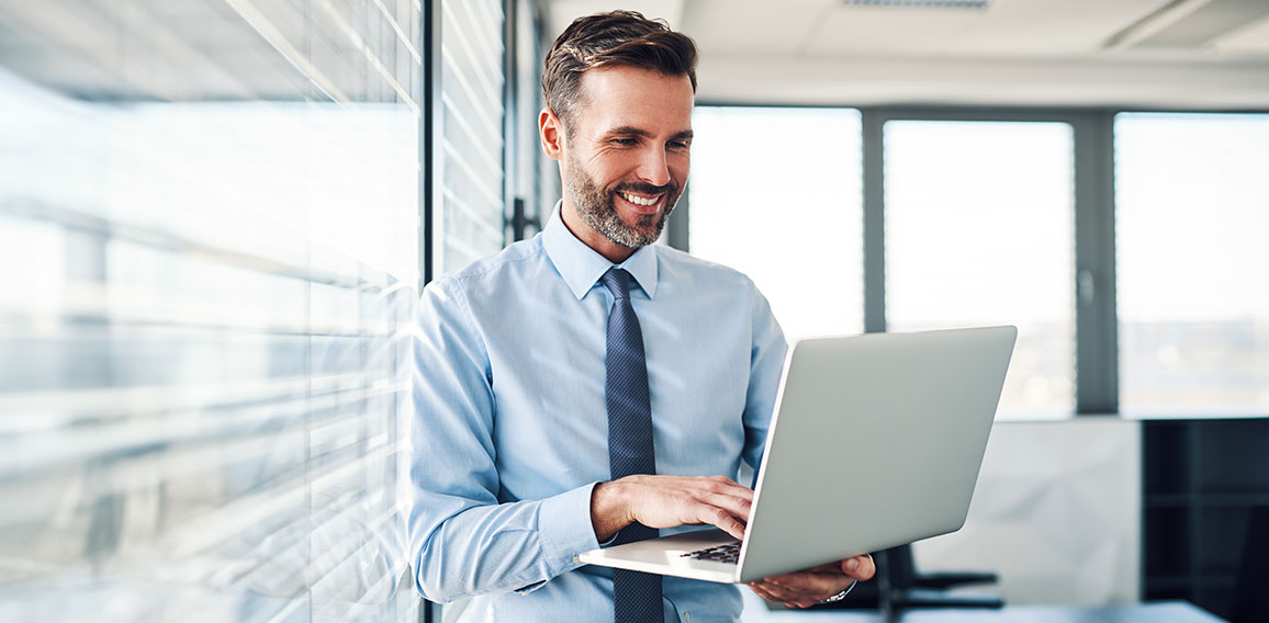 Handsome businessman in modern office looking on laptop