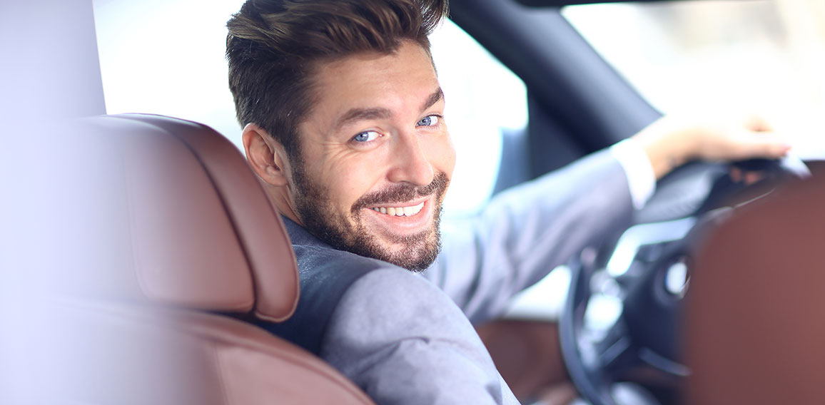 Portrait of an handsome smiling business man driving his car