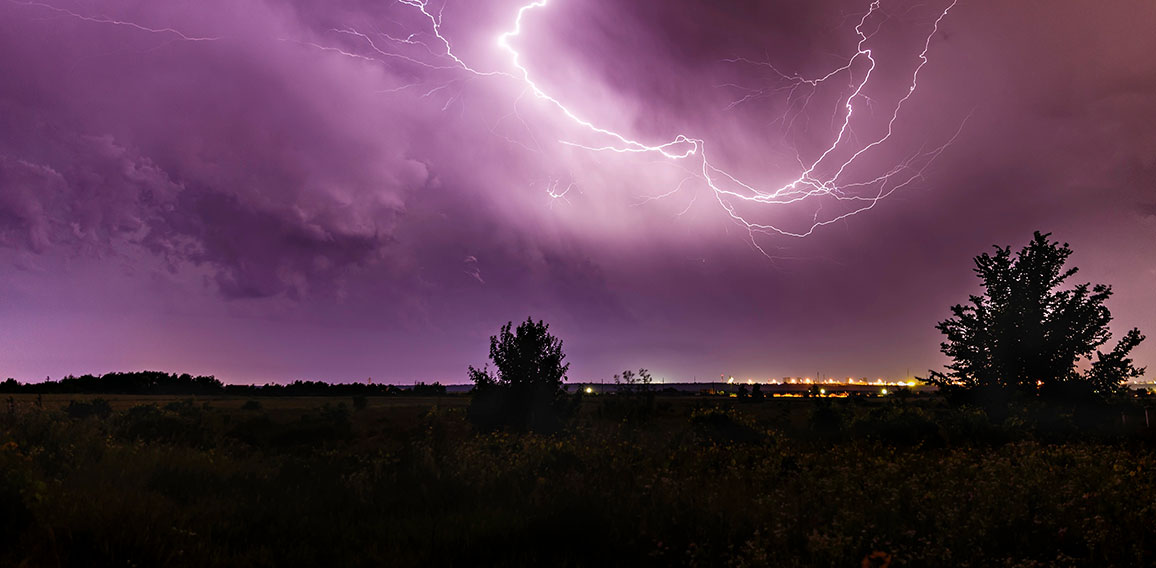 Lightning in the sky at night with a city in the distance