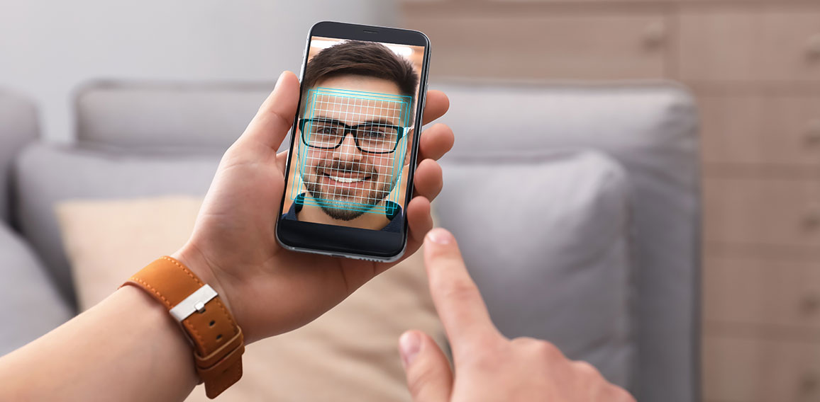 Man using smartphone with facial recognition system indoors, clo