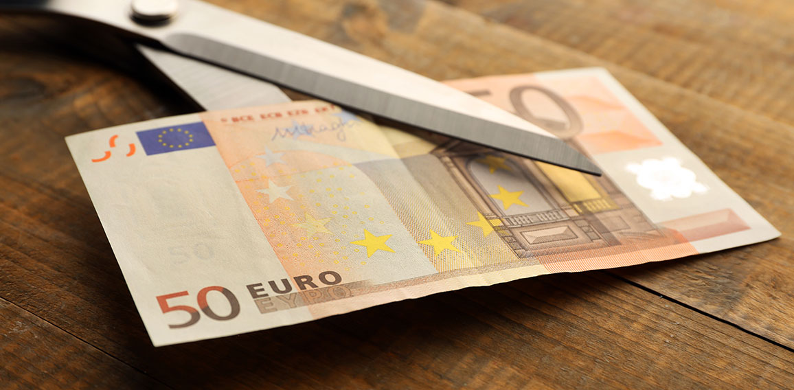 Scissors cuts euro banknote on wooden background