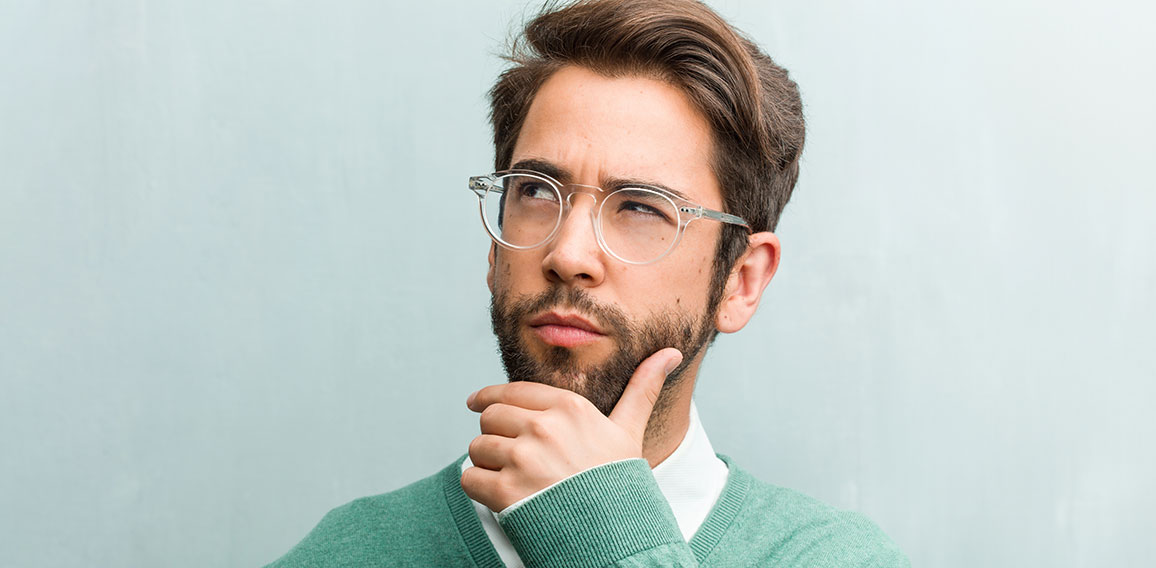 Young handsome entrepreneur man face closeup doubting and confused, thinking of an idea or worried about something