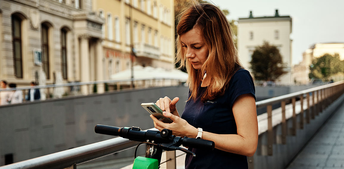 Woman unlock electric scooter for rent with a smartphone application