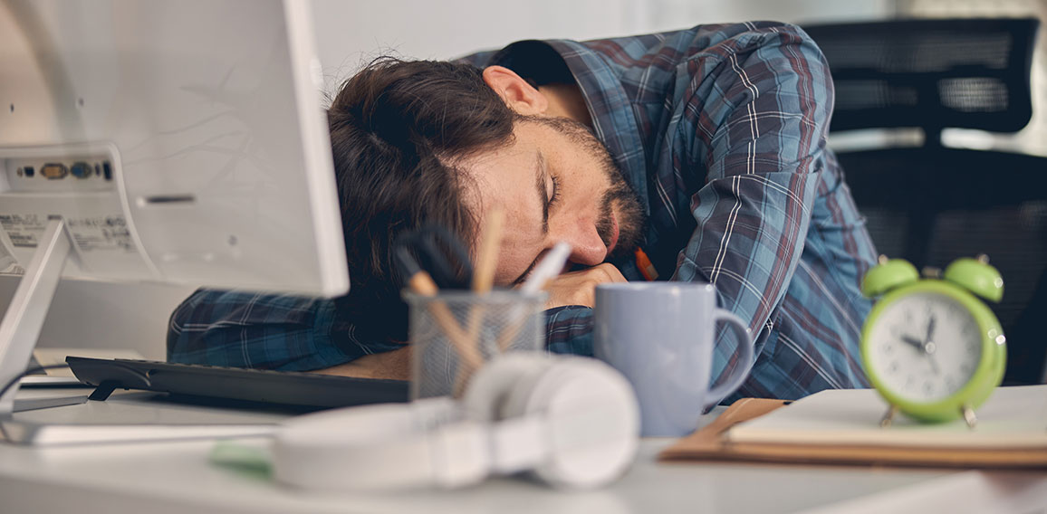 Tired young man taking nap at work