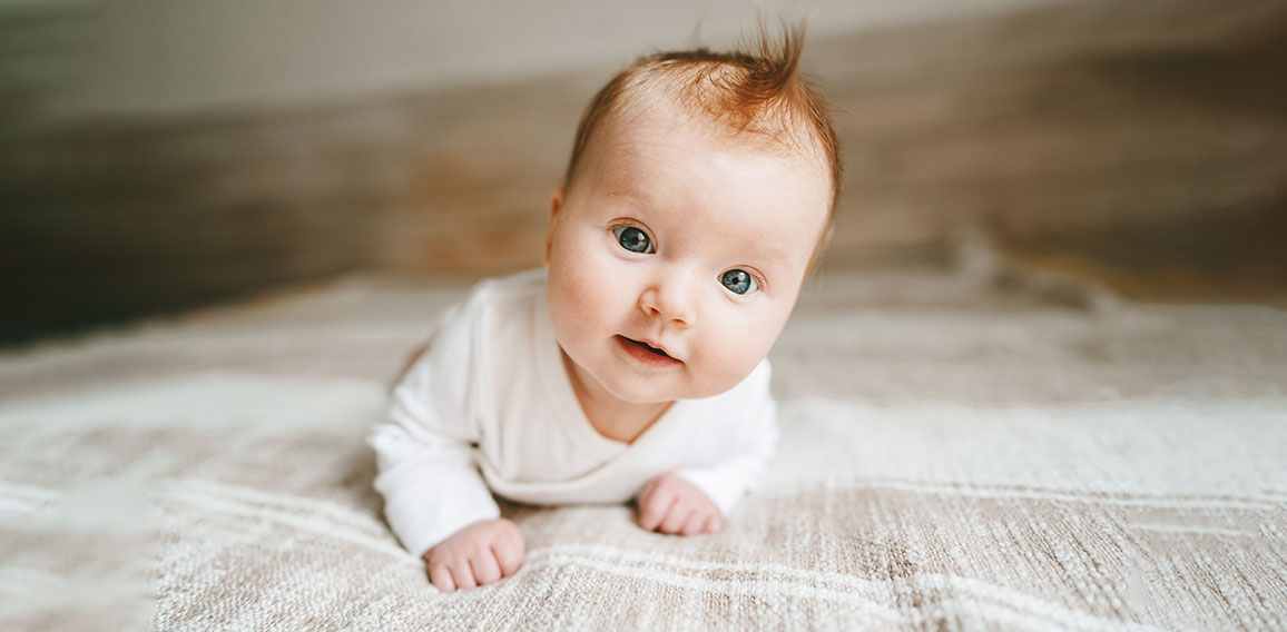 Cute baby ginger hair close up crawling on bed smiling adorable kid portrait family lifestyle 3 month old child