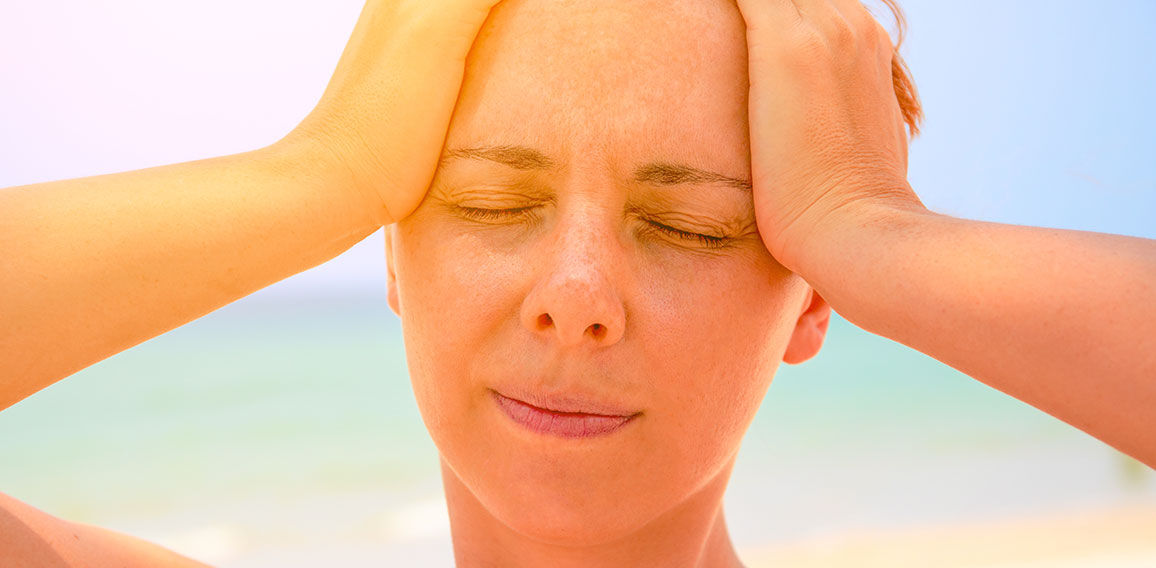 Young woman suffering with headache. Woman on hot beach with sunstroke. Health problem on holiday.