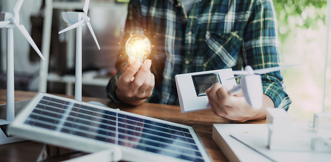 Close-up at a light bulb, An engineer sits holding a light bulb