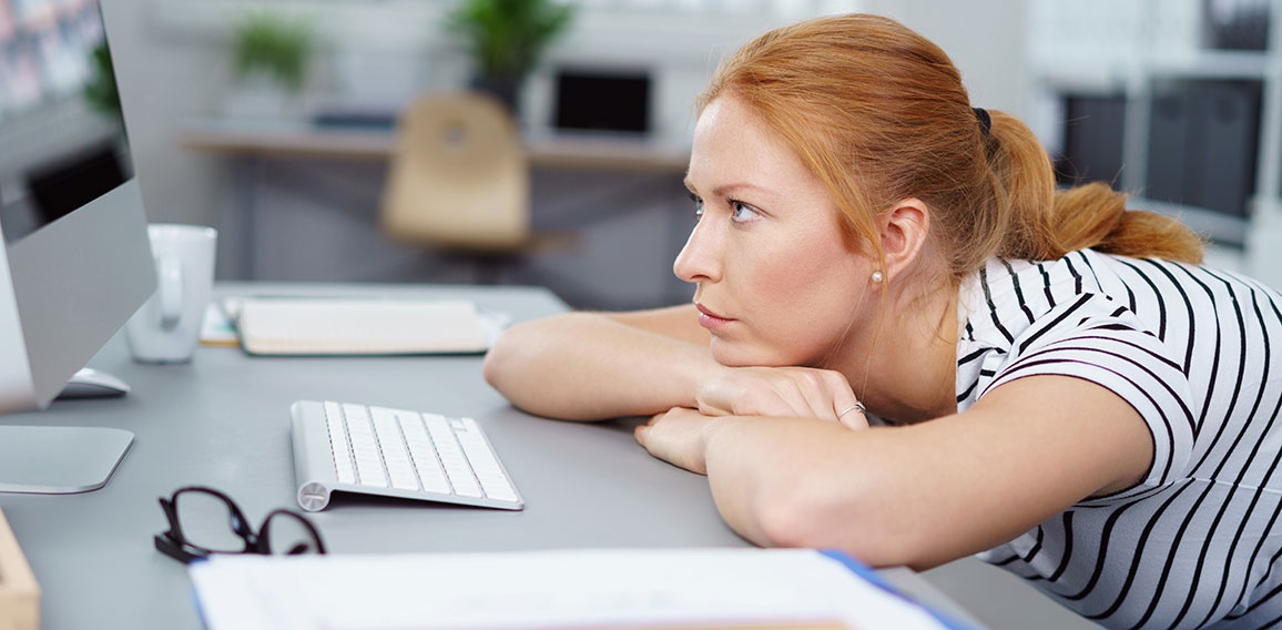 frau im büro schaut genervt auf ihren pc