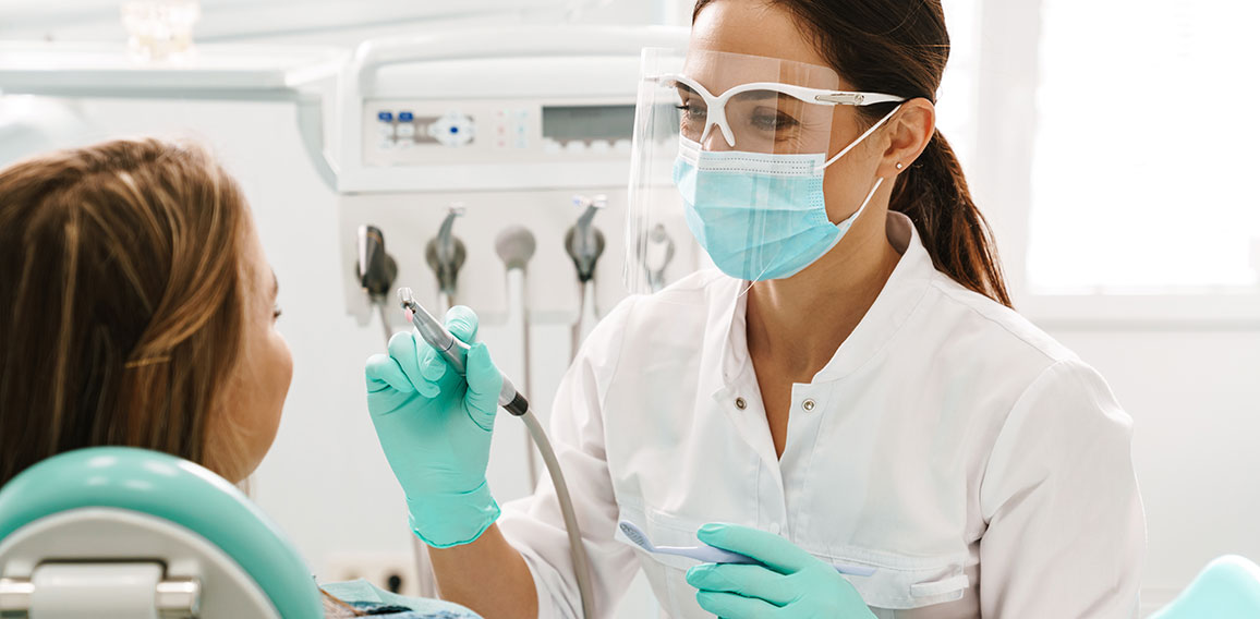 European mid dentist woman in face mask working in dental clinic