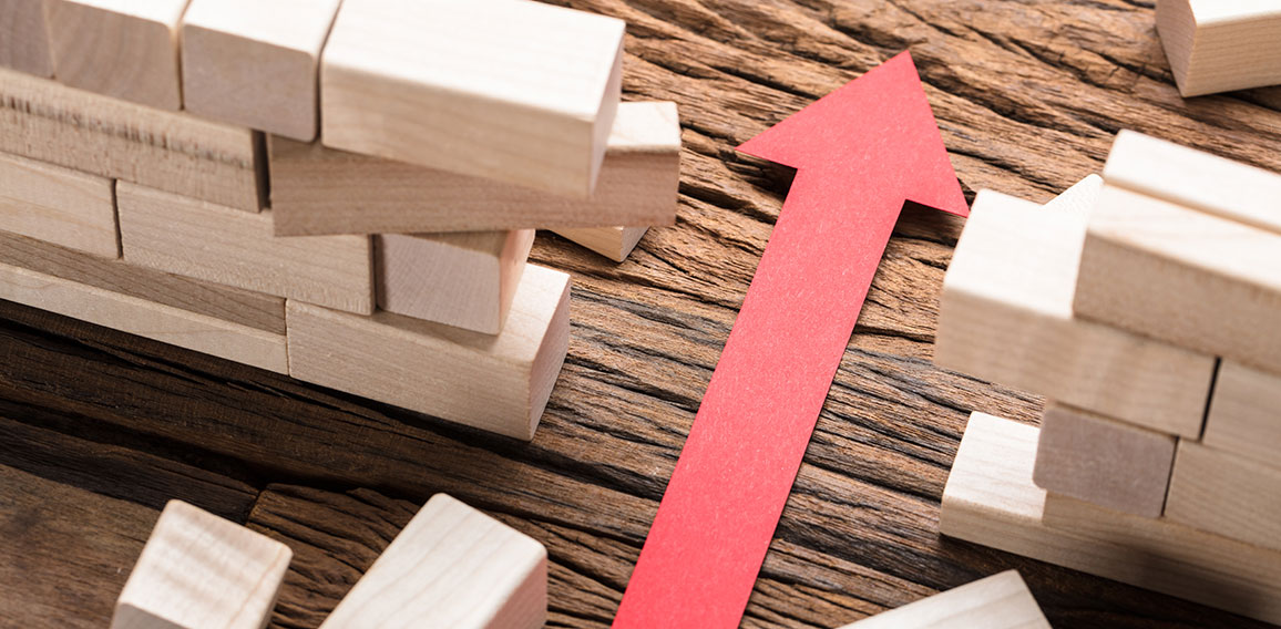 Red Paper Arrow Amidst Blocks On Wooden Table